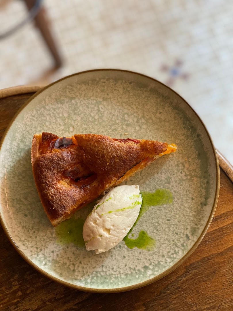Une part de tarte servie avec une quenelle de crème